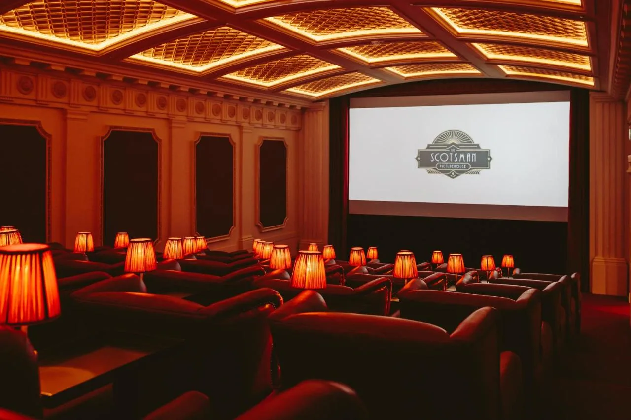 a cinema room with red chairs and a screen at The Scotsman Hotel in Edinburgh